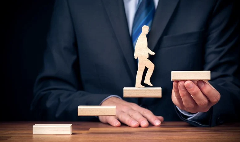 A man in a suit holding floating wooden steps with a wood person silhouette walking.