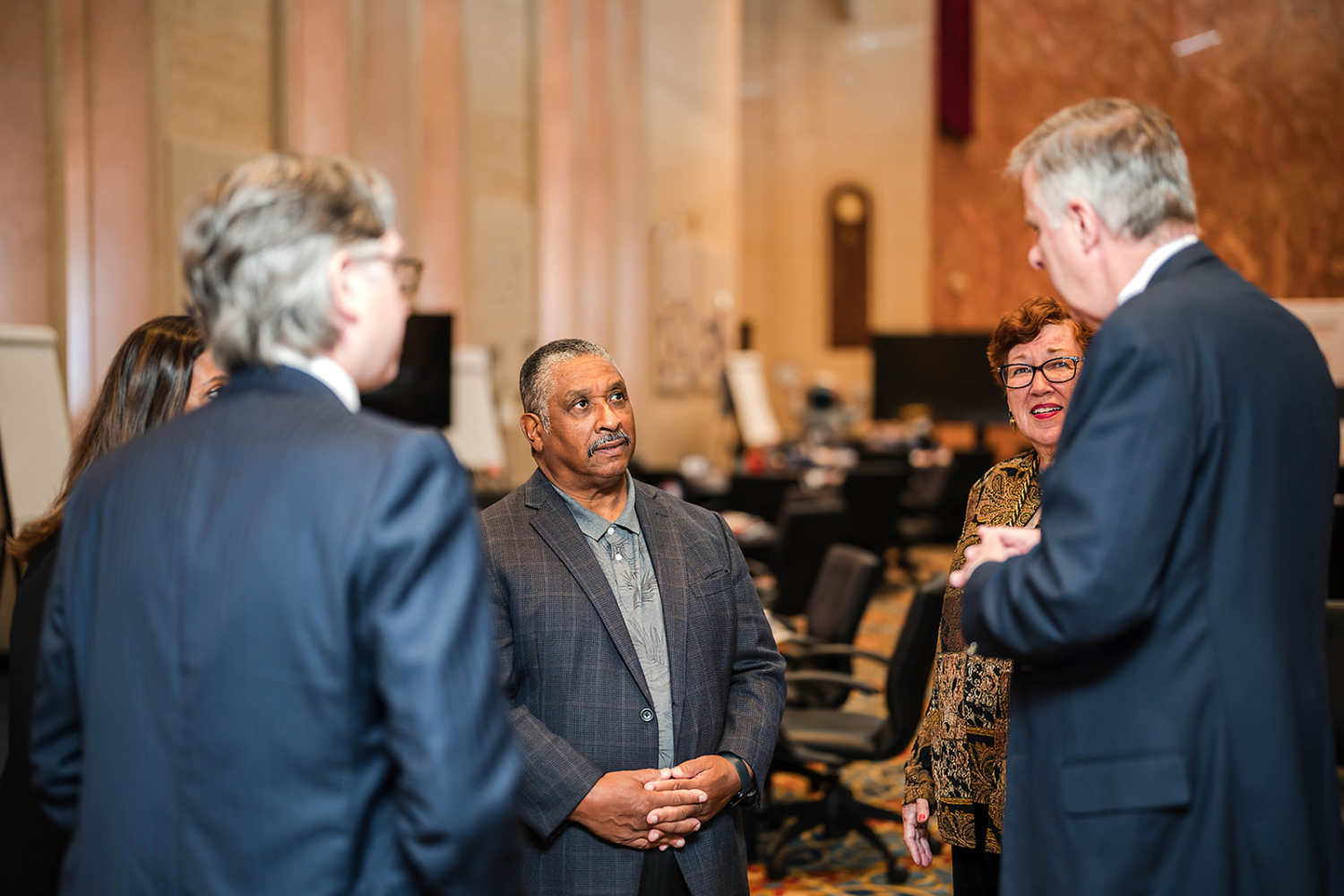 Five professionals stand in a circle talking.